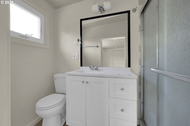 bathroom with vanity, toilet, and a shower with door