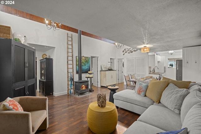 living room with sink, a chandelier, a wood stove, and dark hardwood / wood-style floors