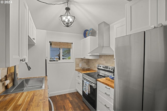 kitchen with stainless steel appliances, butcher block counters, wall chimney range hood, tasteful backsplash, and white cabinetry