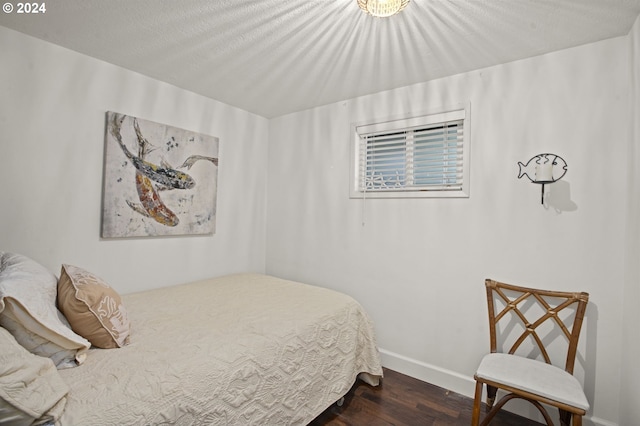 bedroom with a textured ceiling and dark hardwood / wood-style flooring