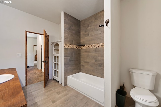 full bathroom featuring vanity, tiled shower / bath combo, hardwood / wood-style floors, and toilet