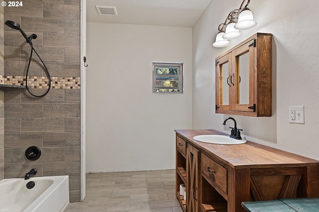 bathroom with hardwood / wood-style floors, tiled shower / bath combo, and vanity