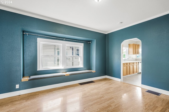 empty room featuring light hardwood / wood-style floors, ornamental molding, and sink