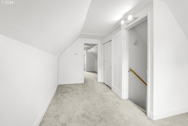 additional living space with vaulted ceiling, a textured ceiling, and light colored carpet