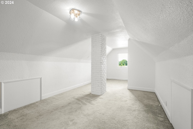 additional living space with a textured ceiling, vaulted ceiling, and carpet floors