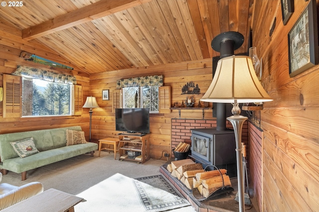 carpeted living area featuring vaulted ceiling with beams, plenty of natural light, a wood stove, and wooden walls