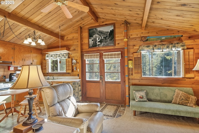 living area featuring vaulted ceiling with beams, wooden ceiling, wooden walls, ceiling fan with notable chandelier, and carpet floors