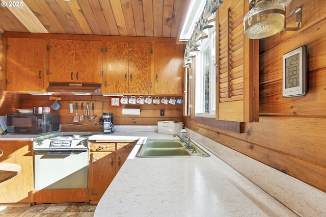 kitchen with range with electric cooktop, light countertops, under cabinet range hood, black microwave, and a sink