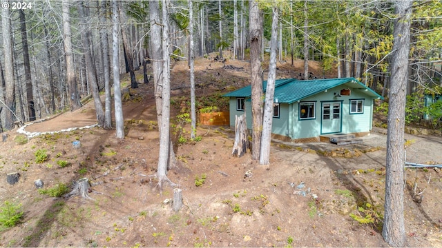 view of outbuilding featuring entry steps, driveway, and a forest view