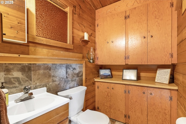 half bathroom featuring wood walls, vanity, and toilet