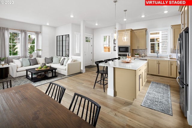 kitchen with a center island, decorative light fixtures, decorative backsplash, stainless steel fridge, and built in microwave