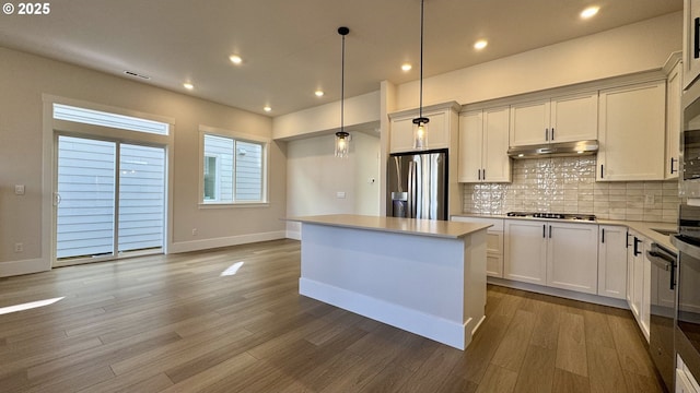 13910 SW 166th Ave, Tigard, OR 97223 - kitchen with stainless steel fridge with ice dispenser, decorative backsplash, wood finished floors, a center island, and light countertops