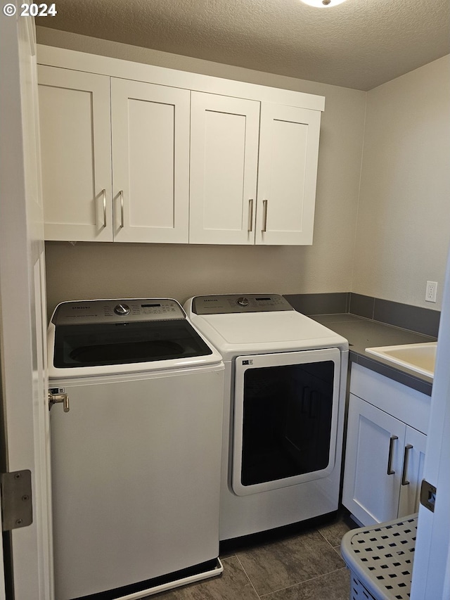 laundry room featuring washer and clothes dryer, cabinets, and a textured ceiling