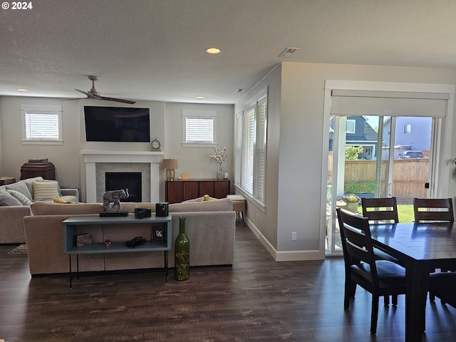 living room featuring ceiling fan, dark wood-type flooring, and a textured ceiling