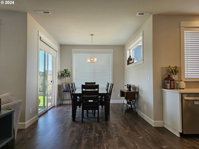 dining space featuring dark hardwood / wood-style flooring, a wealth of natural light, and a notable chandelier