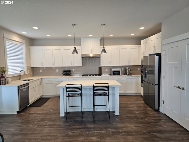 kitchen with stainless steel appliances, white cabinets, a kitchen island, and pendant lighting