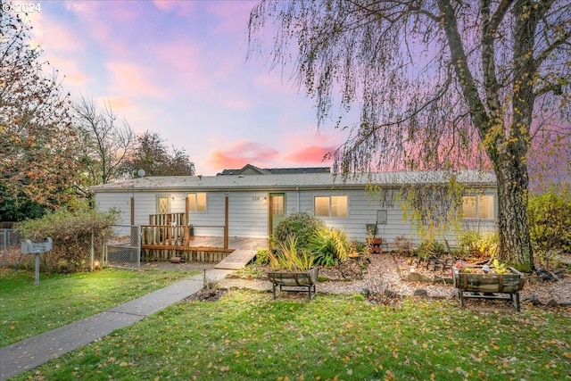 back house at dusk featuring a yard and a wooden deck