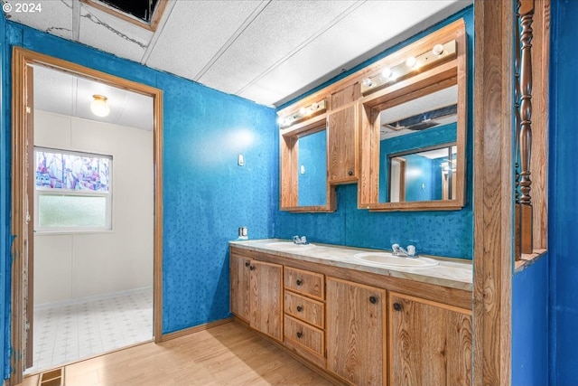 bathroom with hardwood / wood-style floors, vanity, and a drop ceiling