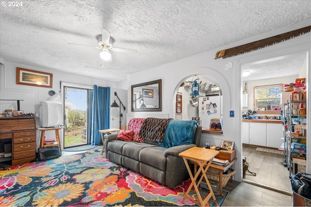 living room with a textured ceiling, ceiling fan, and plenty of natural light