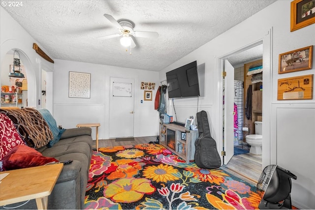 living room with ceiling fan, a textured ceiling, and wood-type flooring