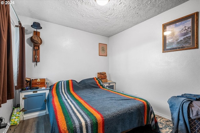 bedroom featuring dark hardwood / wood-style flooring and a textured ceiling