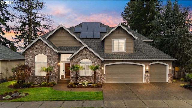 view of front of property featuring a yard, a garage, and solar panels