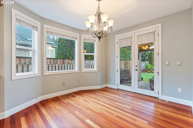 interior space with french doors, an inviting chandelier, and hardwood / wood-style floors