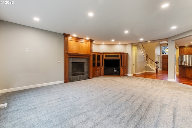 unfurnished living room with a tile fireplace and carpet