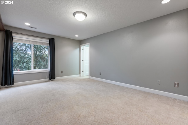 carpeted empty room with a textured ceiling