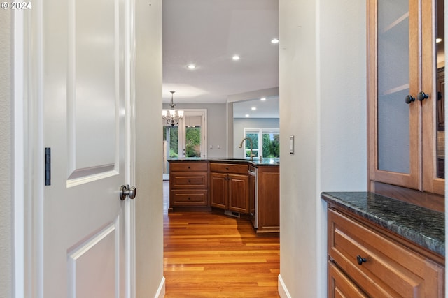 hallway with sink, light wood-type flooring, and a notable chandelier