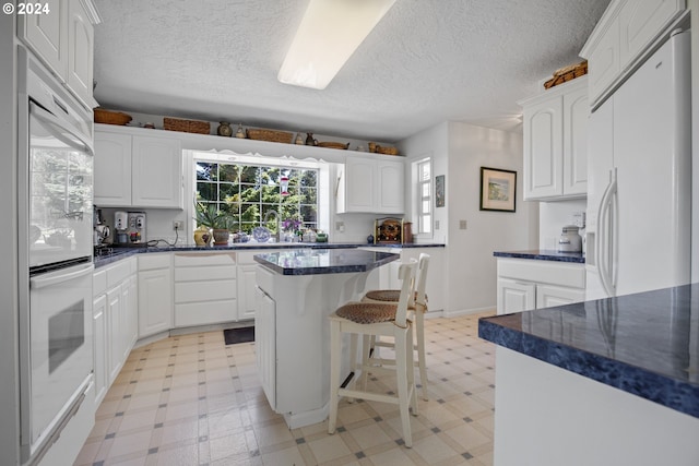 kitchen featuring white cabinets, white appliances, and a kitchen island