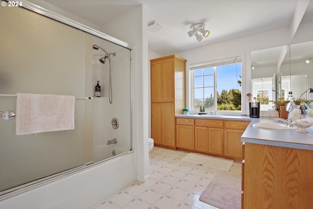 full bathroom featuring combined bath / shower with glass door, vanity, and toilet