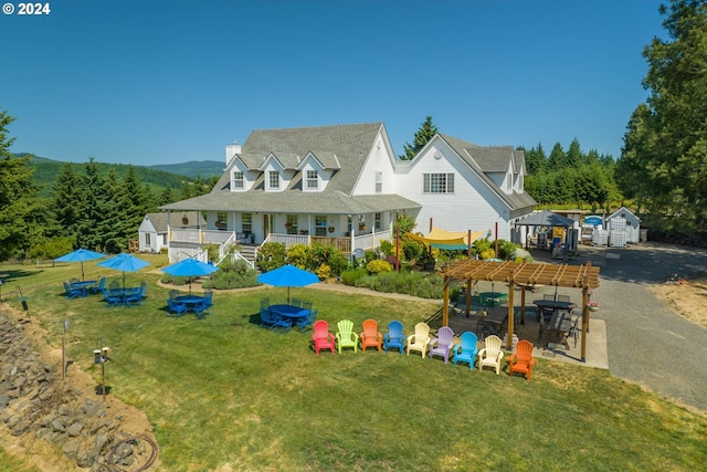 view of front of property with an outbuilding, a pergola, and a front lawn