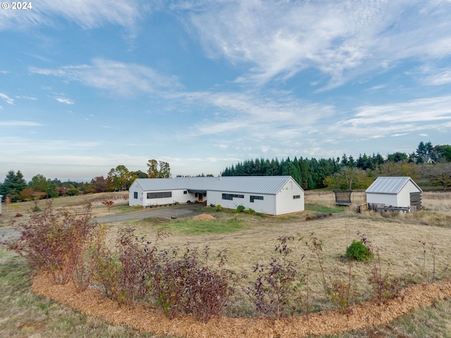 view of front of property featuring an outdoor structure and a rural view