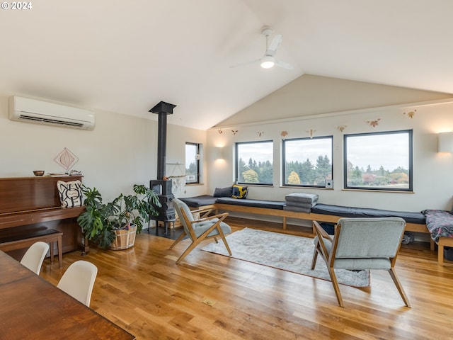 office featuring a wall mounted AC, a wood stove, light hardwood / wood-style floors, lofted ceiling, and ceiling fan