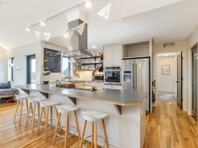 kitchen featuring white cabinets, appliances with stainless steel finishes, a breakfast bar, and light hardwood / wood-style flooring