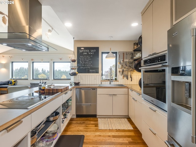 kitchen featuring stainless steel appliances, light wood-type flooring, pendant lighting, sink, and wall chimney exhaust hood