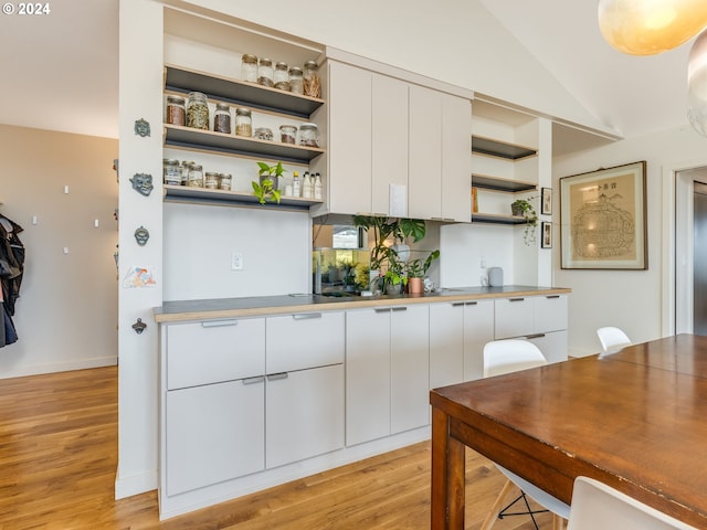 kitchen with white cabinets, light hardwood / wood-style flooring, and vaulted ceiling