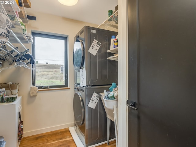 laundry room with stacked washing maching and dryer and wood-type flooring