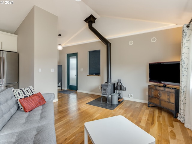 living room featuring light hardwood / wood-style floors, a wood stove, and vaulted ceiling