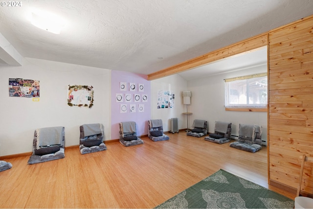 workout room with a textured ceiling, wood-type flooring, and wood walls