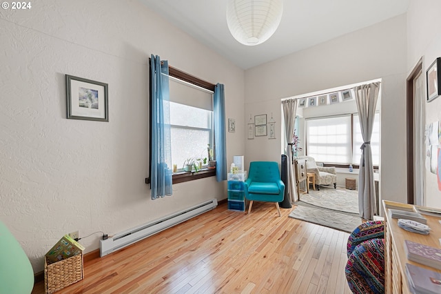 living area with hardwood / wood-style floors and a baseboard heating unit