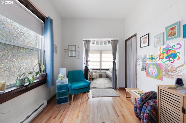 living area with light hardwood / wood-style floors and a baseboard heating unit