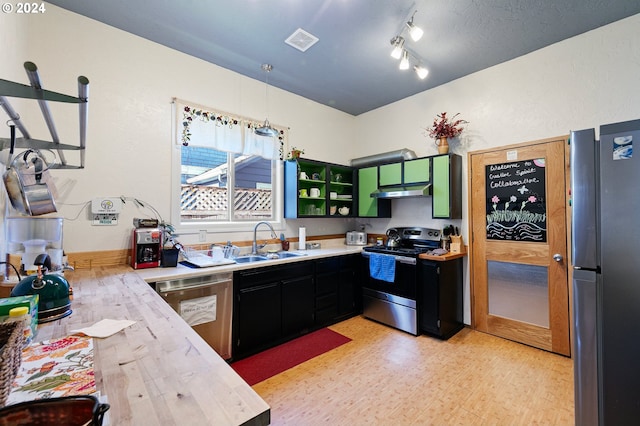 kitchen with appliances with stainless steel finishes, hanging light fixtures, light wood-type flooring, track lighting, and sink