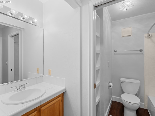 full bathroom with wood-type flooring, vanity, shower / tub combination, and toilet