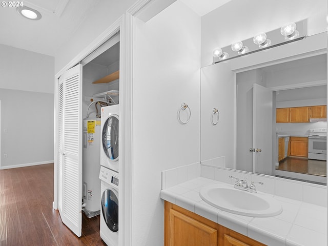 bathroom with wood finished floors, vanity, baseboards, water heater, and stacked washing maching and dryer