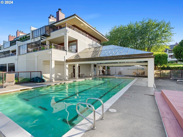 community pool with a patio area, fence, and a gazebo