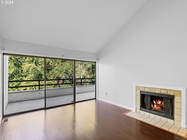 unfurnished living room featuring high vaulted ceiling, a tile fireplace, and wood-type flooring