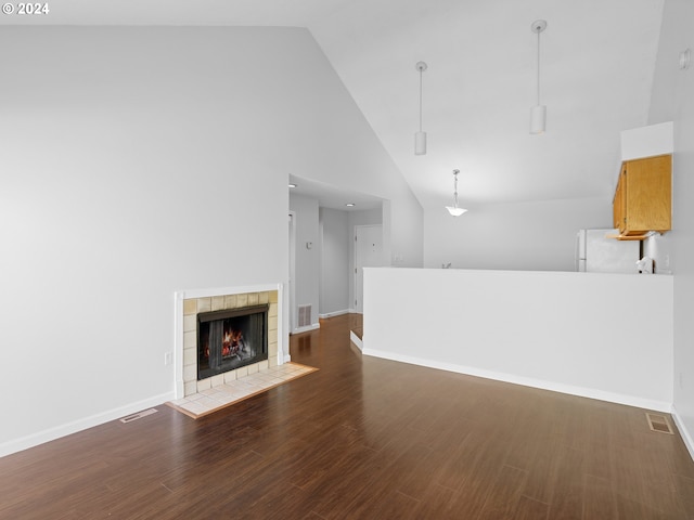 unfurnished living room featuring high vaulted ceiling, dark hardwood / wood-style floors, and a tile fireplace