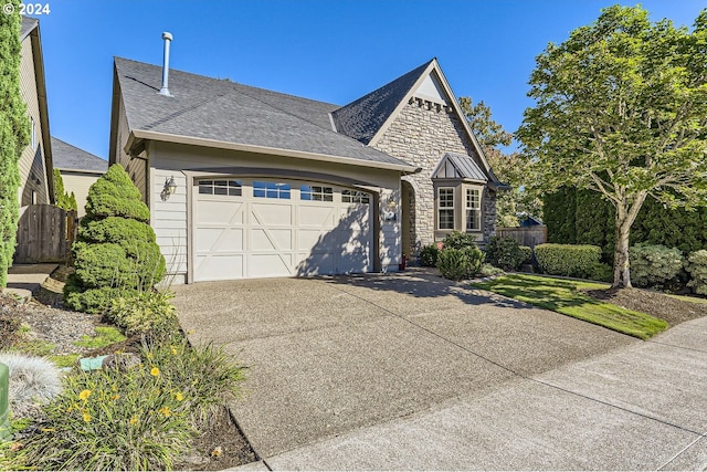 view of front of home with fence, concrete driveway, an attached garage, and stone siding